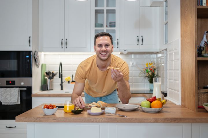 Portrait of a young Caucasian man, having an breakfast on the modern kitchen