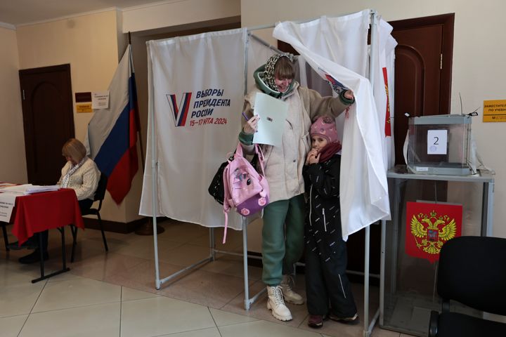 A woman with a girl leave a voting booth during a presidential election in the Pacific port city of Vladivostok, east of Moscow, Russia, Sunday, March 17, 2024. Voters in Russia are heading to the polls for a presidential election that is all but certain to extend President Vladimir Putin's rule after he clamped down on dissent. (AP Photo)