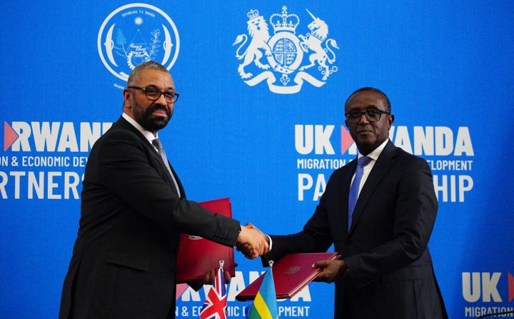 James Cleverly and Rwanda's foreign minister Vincent Biruta exchange documents after signing a new treaty, in Kigali on December 5, 2023. 