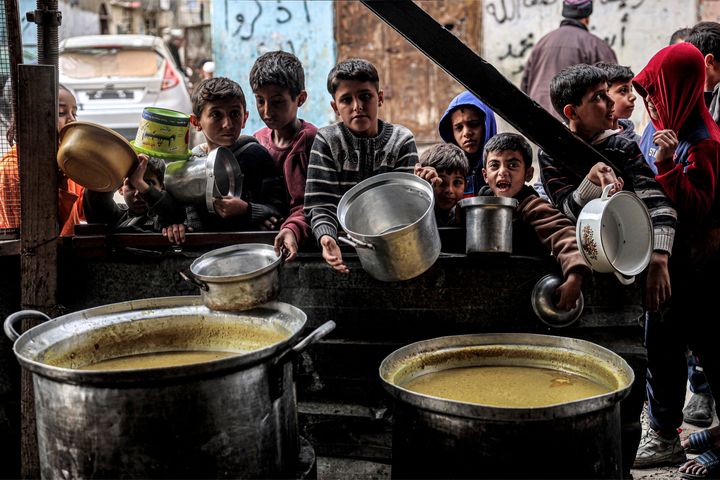 Boys wait while holding empty pots with other displaced Palestinians queueing for meals provided by a charity organization ahead of the fast-breaking "iftar" meal during the Muslim holy month of Ramadan, in Rafah in the southern Gaza Strip on March 16.