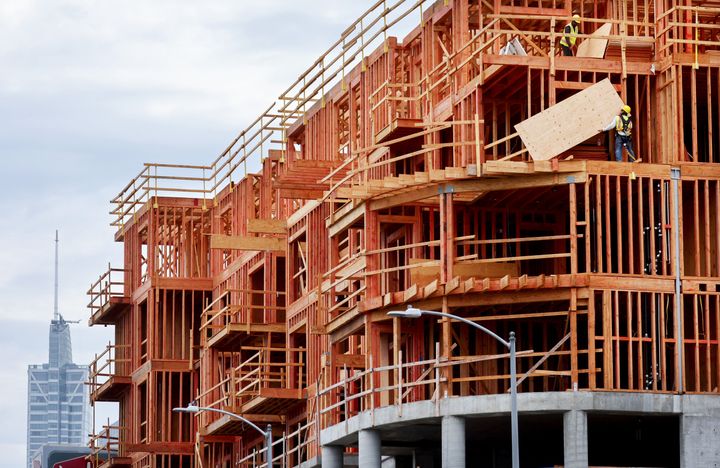 Workers construct new residential housing units on Aug. 04, 2022, in Los Angeles. In some big states, local law requires regulators to adopt the latest and greenest codes automatically.