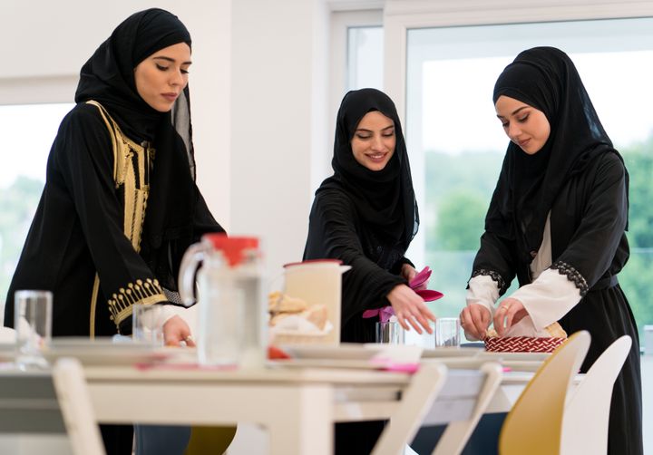 Muslim girls preparing table for family meal