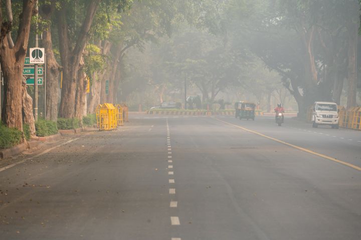 Almost empty boulevard at morning in New Delhi, India. Polluted air looks like fog.