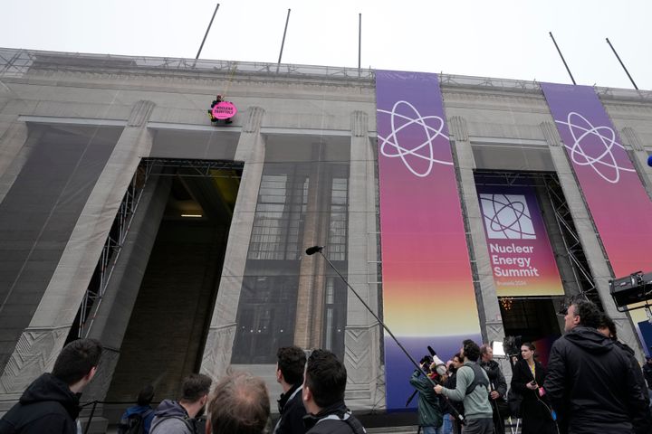Ένας διαδηλωτής της Greenpeace κρέμεται στο κτίριο με ένα πανό κατά τη διάρκεια των αφίξεων για τη Σύνοδο Κορυφής για την Πυρηνική Ενέργεια στις Βρυξέλλες, Πέμπτη 21 Μαρτίου 2024.