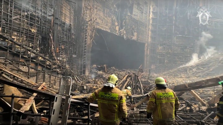 Des pompiers sont vus en train de fouiller dans la salle de concert incendiée un jour après l'attaque.