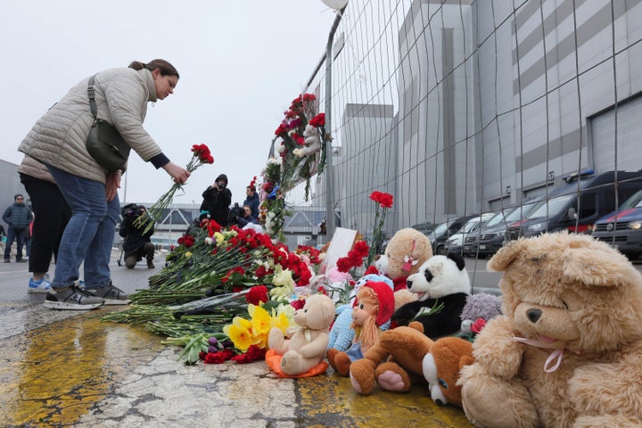 Samedi, une femme dépose des fleurs près de la clôture à côté de l’hôtel de ville de Crocus.