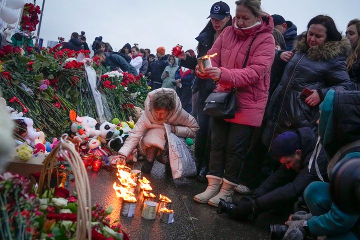 A woman lights candles at the fence next to the Crocus City Hall, on the western edge of Moscow, Russia, on Saturday.