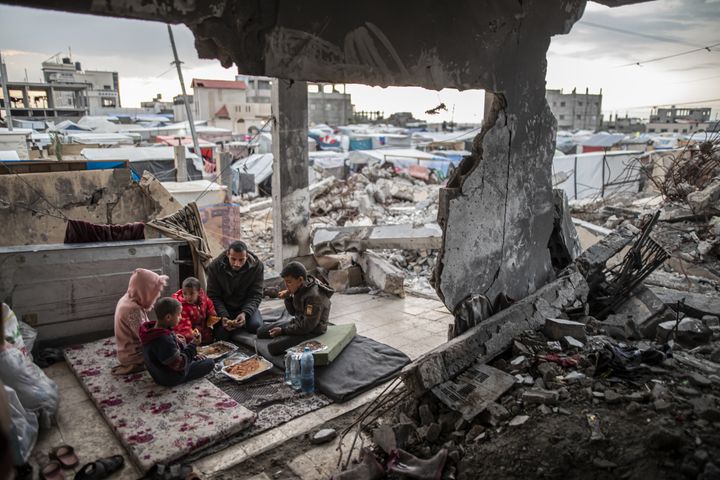 イスラエルの攻撃で破壊された自宅の床で食事をするパレスチナ人家族（2024年3月20日）