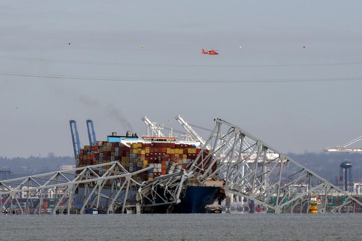 A helicopter flies over a container ship as it rests against wreckage of the Francis Scott Key Bridge on Tuesday.