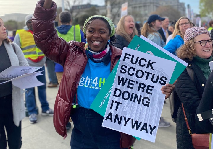 An abortion rights advocate holds signs outside of the Supreme Court as it hears arguments in a case aimed at restricting access to the abortion pill, mifepristone.