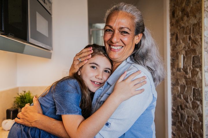 Portrait of a grandmother and granddaughter embraced in the kitchen at home