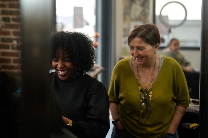 Η κομμώτρια Aude Livoreil-Djampou, δεξιά, γελάει με ένα από τα μέλη του προσωπικού στο κομμωτήριό της, στο Παρίσι, Τετάρτη 27 Μαρτίου 2024