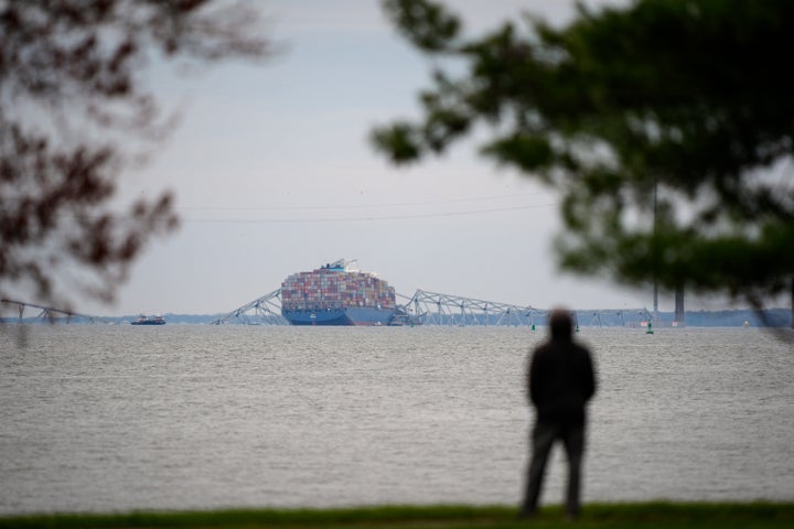 Eine Person schaut von Fort McHenry aus einem Containerschiff zu, das am Donnerstag, 28. März 2024, in Baltimore auf den Trümmern der Francis Scott Key Bridge zur Ruhe kommt.  (AP Photo/Matt Rourke)