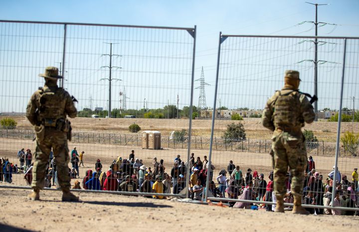Migrants wait in line adjacent to the border fence under the watch of the Texas National Guard to enter into El Paso, Texas, May 10, 2023. (AP Photo/Andres Leighton, File)