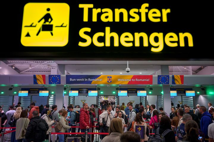 Επιβάτες που φθάνουν στο διεθνές αεροδρόμιο Henri Coanda περνούν κάτω από μια πινακίδα πληροφοριών Σένγκεν, στο Otopeni, κοντά στο Βουκουρέστι της Ρουμανίας, Κυριακή 31 Μαρτίου 2024