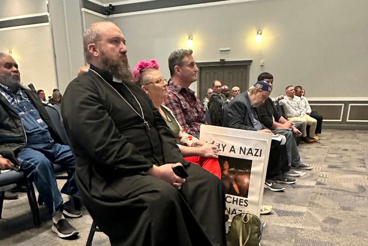 Father James Neal, foreground, pastor of the Holy Cross Orthodox Catholic Church in Enid, Oklahoma, listens during a community forum Tuesday. Judson Blevins, who has acknowledged ties to white supremacist groups, lost a recall vote Tuesday.