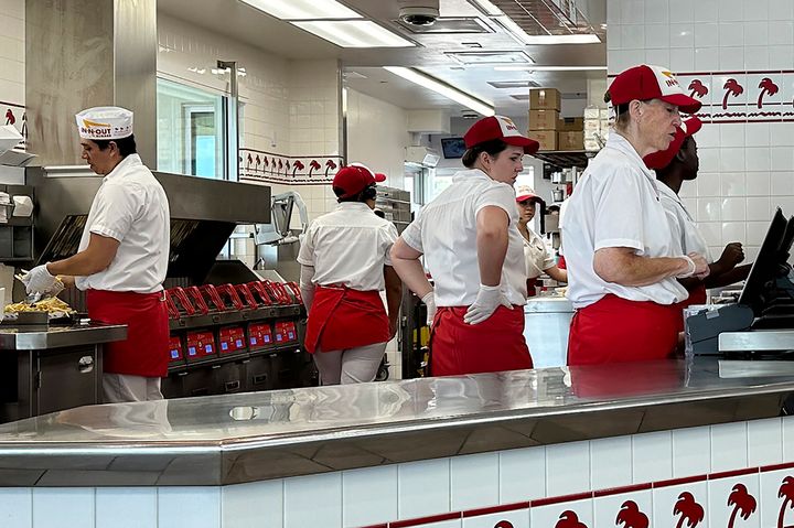 Workers prepare food and take orders an In-N-Out burger restaurant Tuesday, Aug. 8, 2023, in Thornton, Colo. (AP Photo/David Zalubowski)