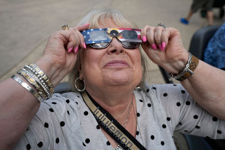 Η Karen Haun, από τη Lantana του Τέξας, χρησιμοποιεί ηλιακά γυαλιά για να παρακολουθήσει την αρχή της ηλιακής έκλειψης, όπως φαίνεται από το Fort Worth του Τέξας, τη Δευτέρα 8 Απριλίου 2024