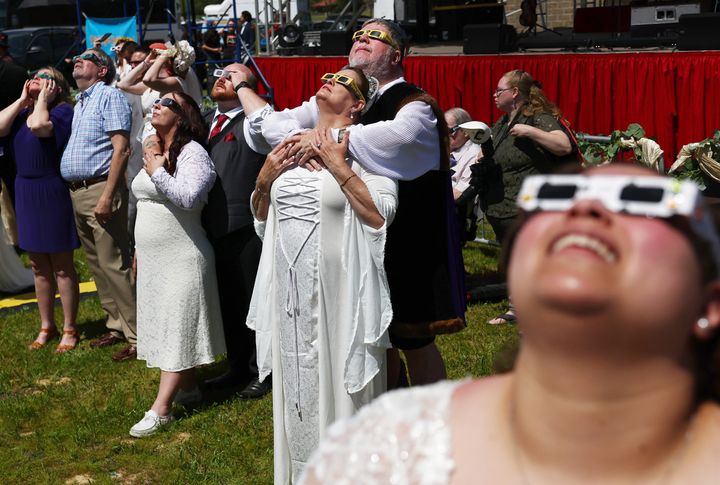 Couples view the solar eclipse during a mass wedding at the Total Eclipse of the Heart festival on April 8, 2024 in Russellville, Arkansas. (Photo by Mario Tama/Getty Images)