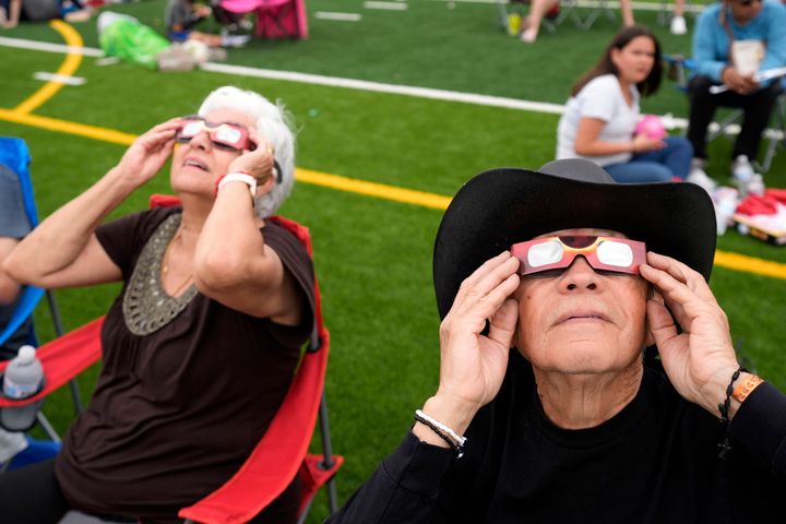 Al Angel Flores, right, watches as the moon partially covers the sun during a total solar eclipse, as seen from Eagle Pass, Texas, Monday, April 8, 2024. (AP Photo/Eric Gay)