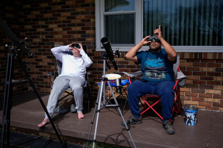 Melissa, left, and Michael Richards watch through solar goggles as the moon partially covers the sun during a total solar eclipse, as seen from Wooster, Ohio, Monday, April 8, 2024. (AP Photo/Erin Hooley)