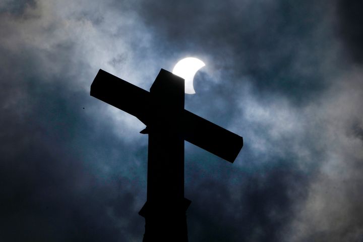 Clouds part as a partial eclipse of the sun and moon cross atop the New Sweden Evangelical Lutheran Church steeple Monday, April 8, 2024, in Manor, Texas. (AP Photo/Charles Rex Arbogast)