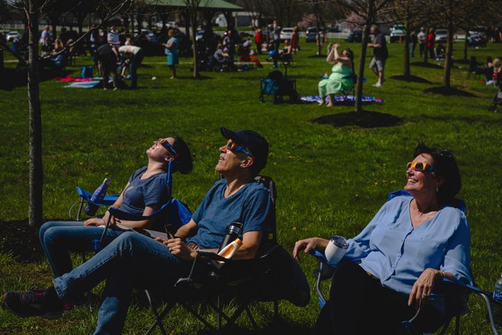 Attendees look on at the total solar eclipse in progress ahead of a mass wedding ceremony at Trenton Community Park, Monday, April 8, 2024, in Trenton, Ohio. (AP Photo/Jon Cherry)