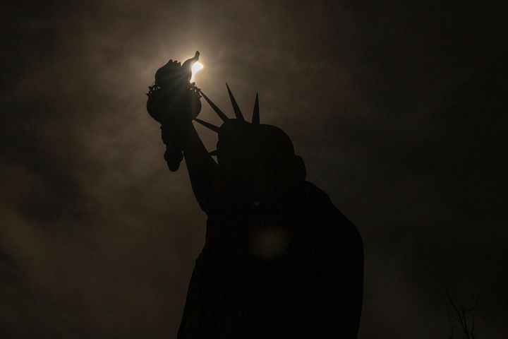 Το φεγγάρι καλύπτει εν μέρει τον ήλιο πίσω από το Άγαλμα της Ελευθερίας κατά τη διάρκεια μιας ηλιακής έκλειψης, Δευτέρα, 8 Απριλίου 2024, στη Νέα Υόρκη. (AP Photo/Yuki Iwamura)