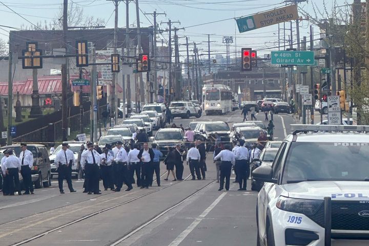 Police and officials gather on a cordoned off street at the scene of the shooting.