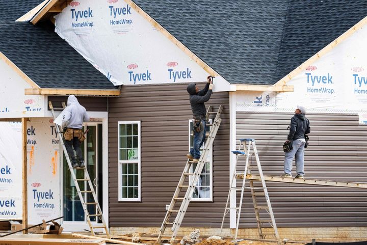 Workers attach siding to a house at a new home construction site in Trappe, Maryland, on October 28, 2022. 
