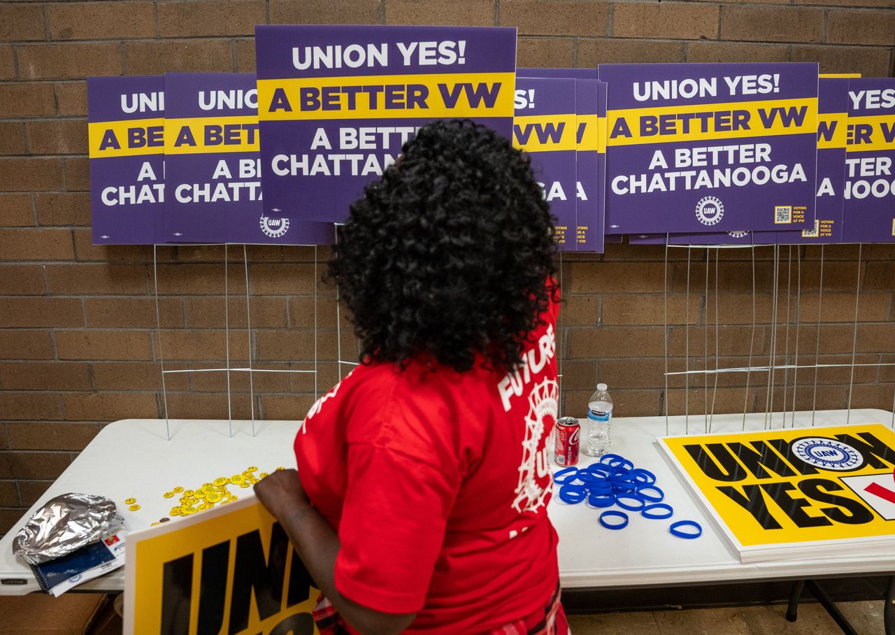 A woman takes a UAW yard sign at a local union hall in Chattanooga.