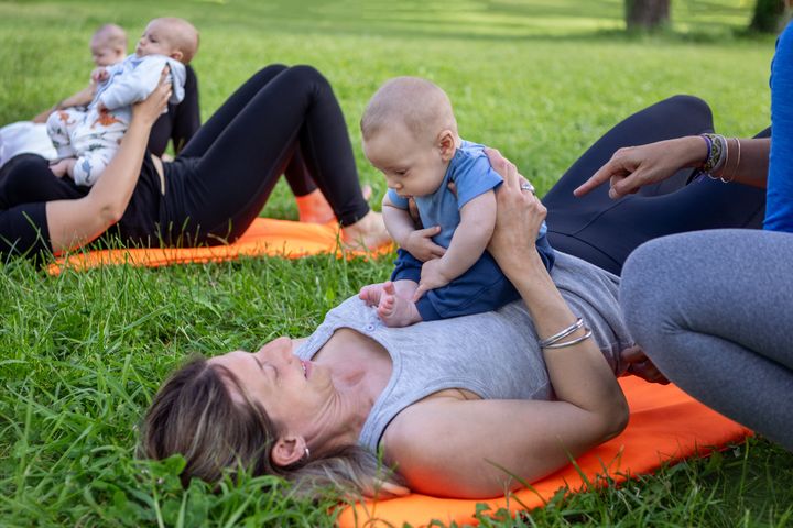 Group of women exercising with their babies in the park.