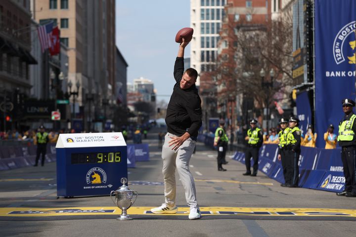 Boston Marathon grand marshal Rob Gronkowski spikes a football next to the trophy during the Boston Marathon on Monday.