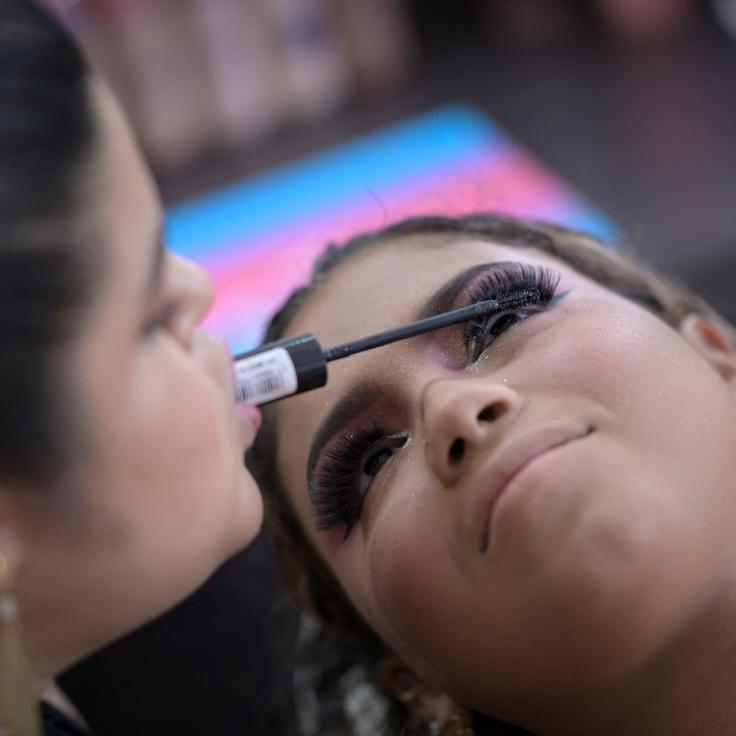 Clélia Rodrigues, who was born with arthrogryposis, applies eye makeup to a client in her salon in Visconde do Rio Branco, Brazil, on March 7, 2023. Rodrigues, whose condition limits her arm movements, has become a successful makeup artist with a large following on social media.