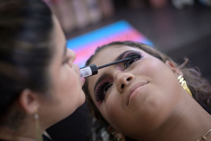 Clélia Rodrigues, who was born with arthrogryposis, applies eye makeup to a client in her salon in Visconde do Rio Branco, Brazil, on March 7, 2023. Rodrigues, whose condition limits her arm movements, has become a successful makeup artist with a large following on social media.