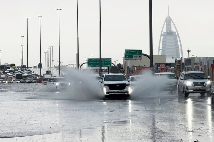 An SUV splashes through standing water on a road with the Burj Al Arab luxury hotel seen in the background in Dubai, United Arab Emirates, on April 16, 2024.