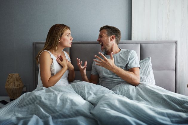 Displeased couple arguing about problems in their relationship during morning time in a bed. Copy space.