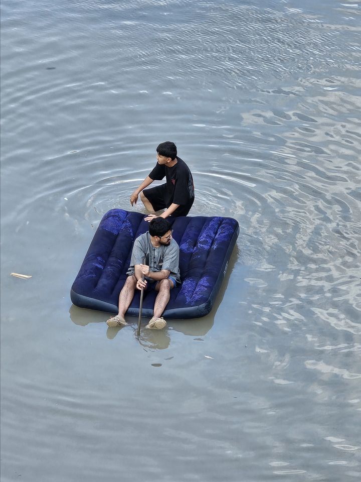 Δύο άνδρες χρησιμοποιούν ένα φουσκωτό κρεβάτι για να επιπλεύσουν πάνω από το νερό καθώς η νεροποντή προκαλεί έντονες πλημμύρες στο Ντουμπάι, Ηνωμένα Αραβικά Εμιράτα, στις 17 Απριλίου 2024.