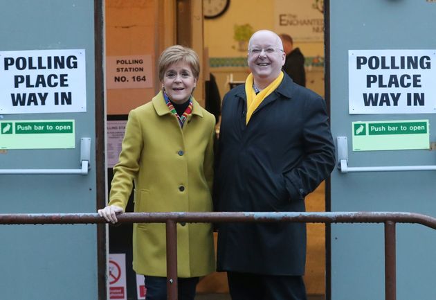Scottish First Minister Nicola Sturgeon poses with husband Peter Murrell, outside polling station for the general election in Glasgow, Scotland, Thursday, Dec. 12, 2019.
