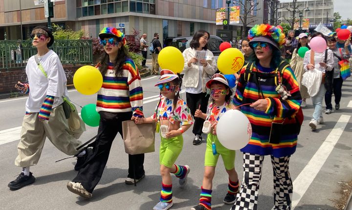 様々なかたちの家族が、色とりどりの風船を持ってパレードを歩いた