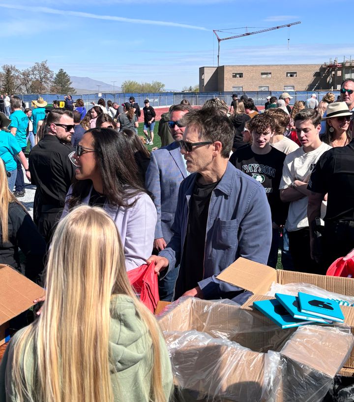 In this photo provided by Jesse Sorenson, actor Kevin Bacon, center, helps fill care packages for his charity, Saturday, April 20, 2024, in Payson, Utah, while visiting the Utah high school where cult classic "Footloose," was filmed. (Jesse Sorenson via AP)