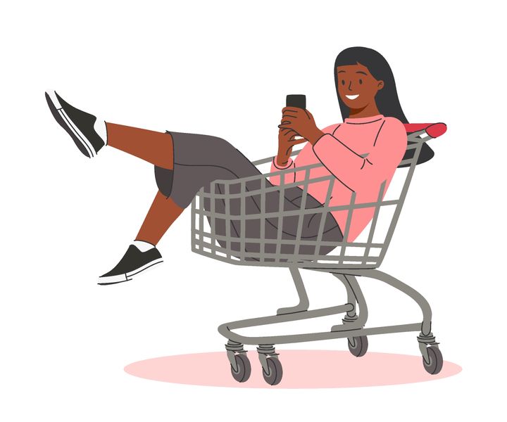 A woman sitting in a shopping cart texting on her phone
