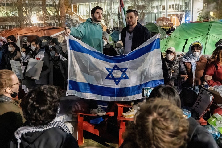 Zwei antiisraelische Demonstranten stehen auf Gartenstühlen und streiten sich mit Palästina-Anhängern bei einem Protest in einem Camp der Northeastern University.  Neben der Angst vor einem Eingreifen der Polizei tauschten pro-palästinensische und pro-israelische Studenten Parolen aus.  Irgendwann entfernte die Campus-Polizei pro-israelische Demonstranten, als die Spannungen zunahmen.