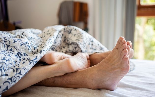 Cropped shot of the feet of a romantic couple under the sheets on the bed