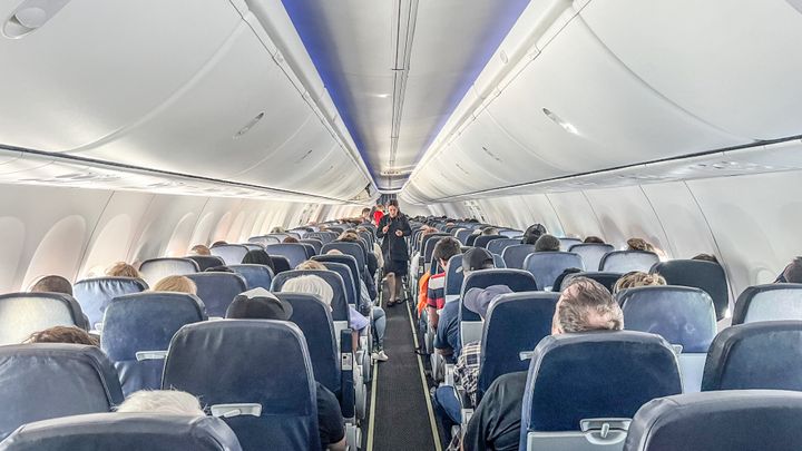 Rear view of interior of airplane with people and stewardess during day in Cuba