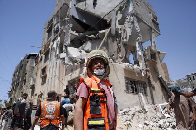 Civil defence team stands in front of destroyed building in Rafah, Gaza.