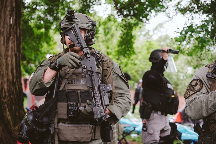 CHARLOTTESVILLE, VIRGINIA - MAY 04: An armed police hides his face from being photographed as the police tries to disperse protesters from the encampment on university grounds. on May 4, 2024 in Charlottesville, Virginia. Pro-Palestinian encampments have sprung up at college campuses around the country with some demonstrators calling for schools to divest from Israeli interests amid the ongoing war in Gaza. (Photo by Eze Amos/Getty Images)