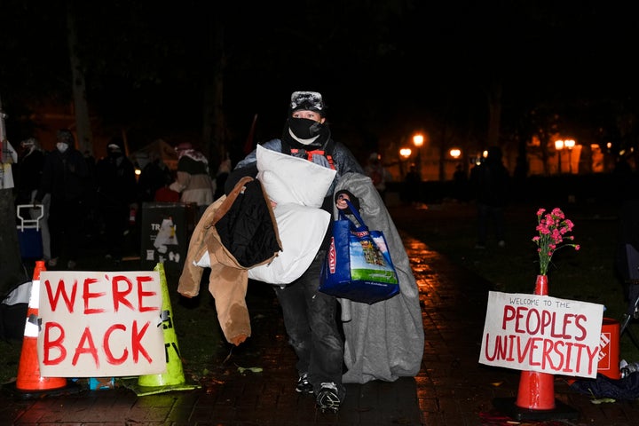 People carry belongings out of an encampment set up by pro-Palestinian demonstrators after police arrived for a raid on the campus at the University of Southern California Sunday, May 5, 2024, in Los Angeles.