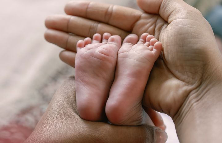 Mother holds baby feet on her hand