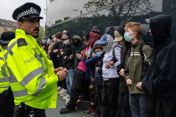 Police officers prepare to move protesters surrounding a bus that was to be used to carry migrants from a hotel on May 2, 2024 in Peckham.